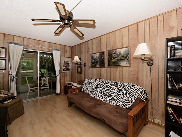 living room featuring wooden walls, light wood-type flooring, and ceiling fan