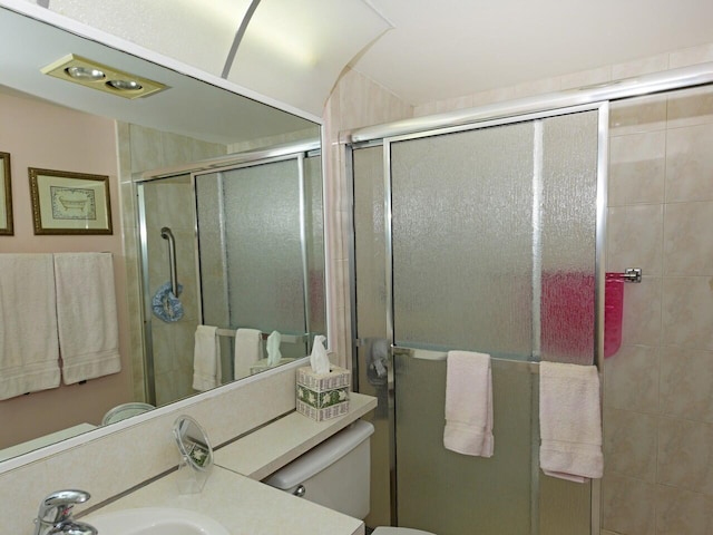 bathroom featuring a shower with door, toilet, and vanity