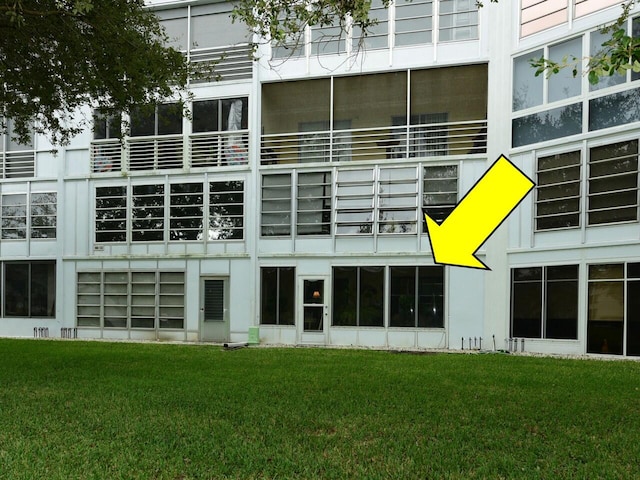 rear view of house featuring a balcony and a lawn