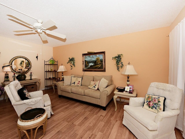 living room with light hardwood / wood-style flooring, a textured ceiling, and ceiling fan