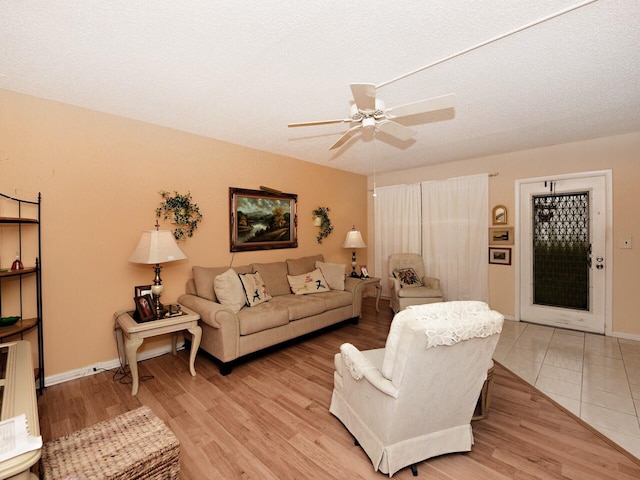 living room with ceiling fan, a textured ceiling, and light hardwood / wood-style flooring