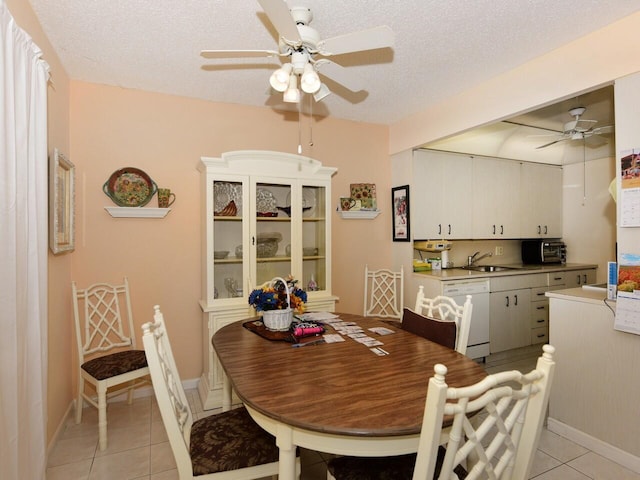 dining space featuring a textured ceiling, sink, light tile patterned floors, and ceiling fan