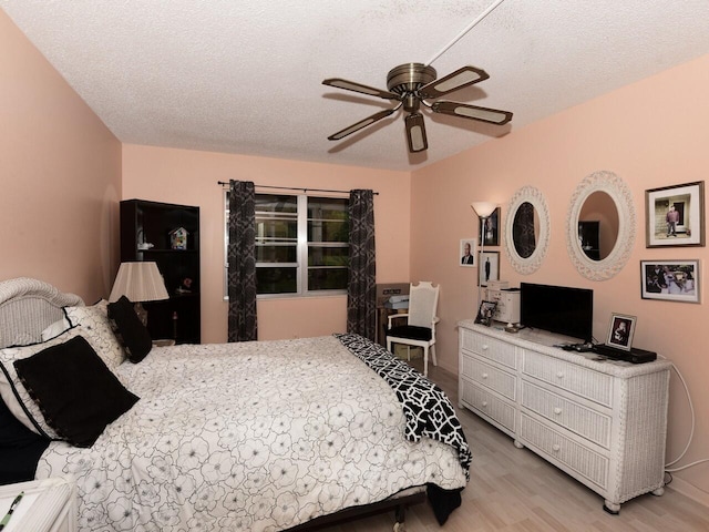 bedroom with a textured ceiling, light wood-type flooring, and ceiling fan