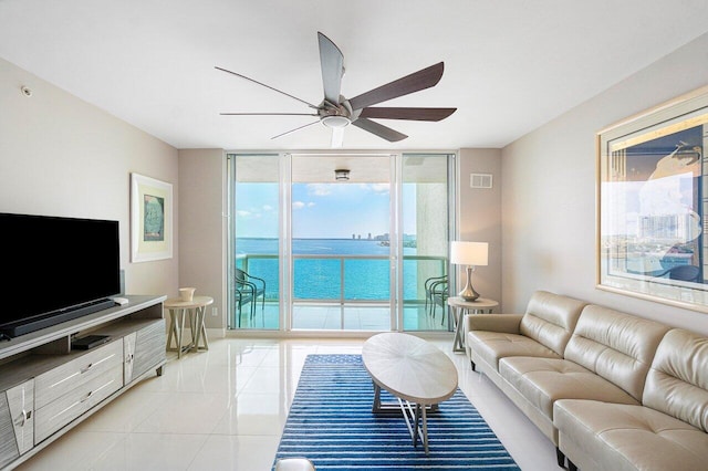 tiled living room featuring plenty of natural light, a water view, and ceiling fan