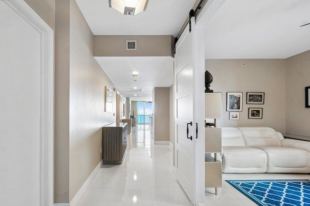 hallway featuring a barn door and light tile patterned floors