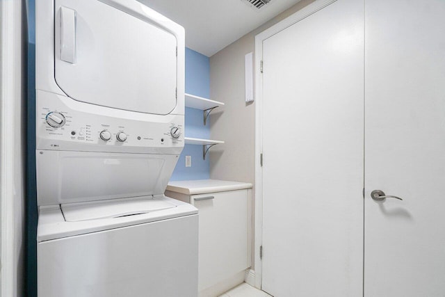 laundry room with stacked washer / drying machine and cabinets