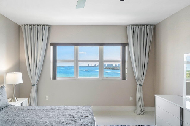 bedroom with light tile patterned floors, a water view, multiple windows, and ceiling fan