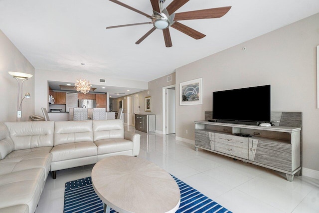 tiled living room featuring ceiling fan with notable chandelier