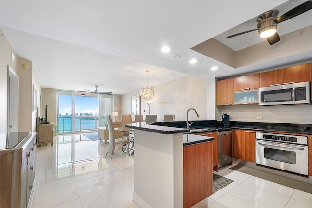 kitchen with stainless steel appliances, sink, kitchen peninsula, an inviting chandelier, and hanging light fixtures