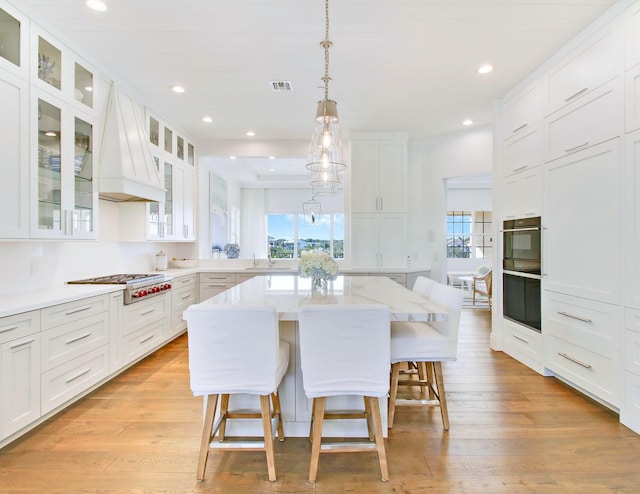 kitchen featuring white cabinets, custom range hood, a breakfast bar, and a kitchen island