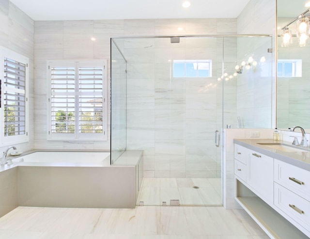 bathroom featuring plus walk in shower, vanity, and tile walls