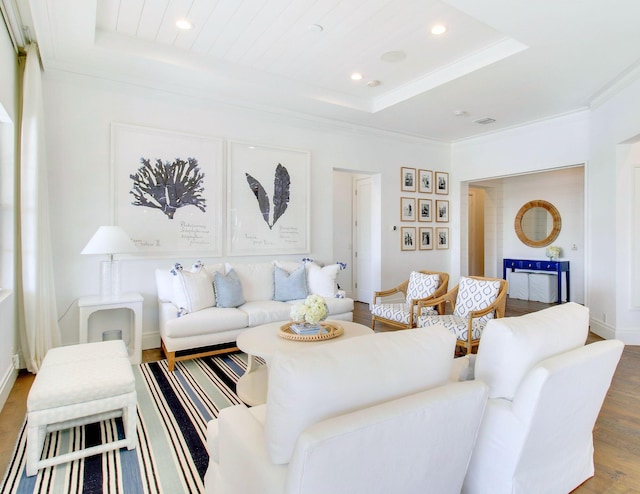 living room featuring a tray ceiling, crown molding, and wood-type flooring