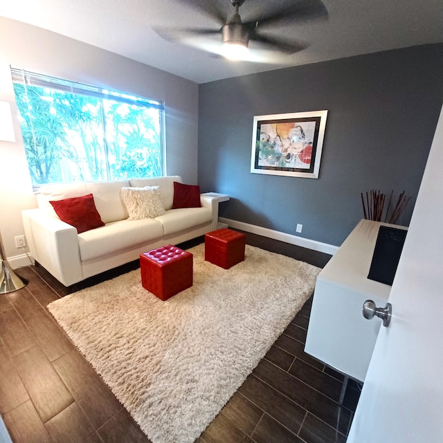 living area featuring wood tiled floor, baseboards, and ceiling fan