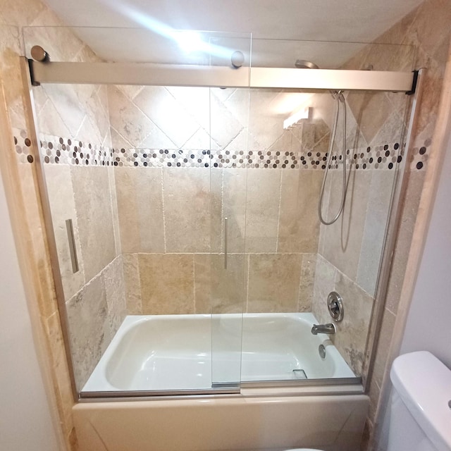 full bath featuring toilet and bath / shower combo with glass door