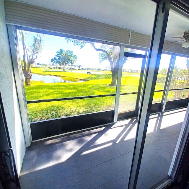 unfurnished sunroom with ceiling fan and a water view