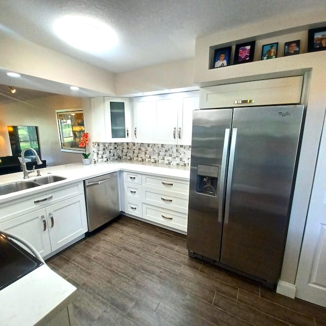 kitchen with white cabinets, decorative backsplash, glass insert cabinets, appliances with stainless steel finishes, and light countertops