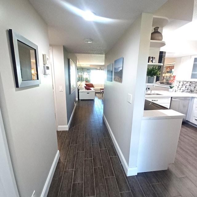 hall with wood finish floors, a sink, and baseboards