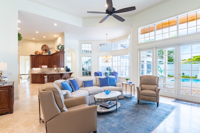 living room with a towering ceiling, french doors, ornamental molding, and ceiling fan with notable chandelier