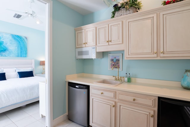 kitchen with sink, light tile patterned floors, cream cabinets, and dishwasher