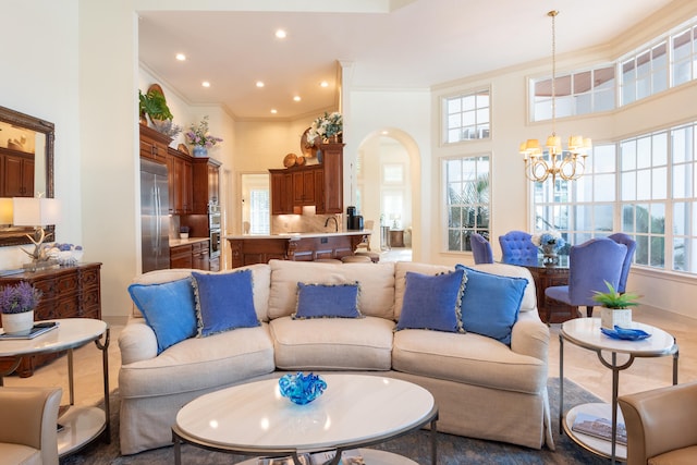 living room with hardwood / wood-style floors, ornamental molding, a high ceiling, and an inviting chandelier