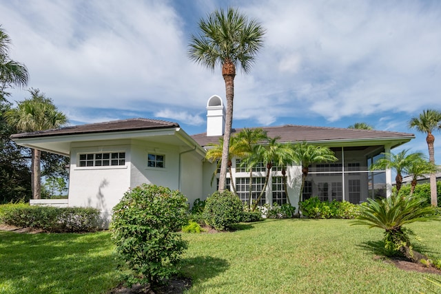 back of house with a sunroom and a lawn