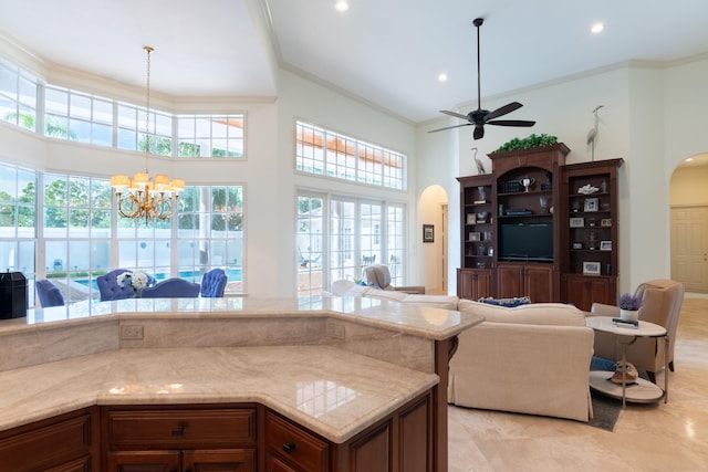 kitchen featuring crown molding, light tile patterned flooring, pendant lighting, a towering ceiling, and ceiling fan with notable chandelier