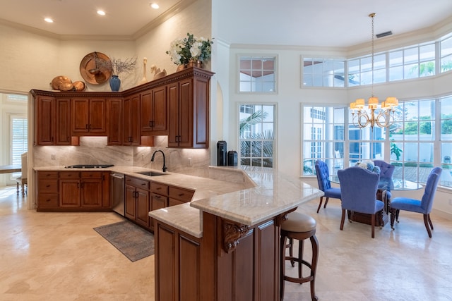 kitchen featuring a high ceiling, kitchen peninsula, sink, pendant lighting, and a chandelier