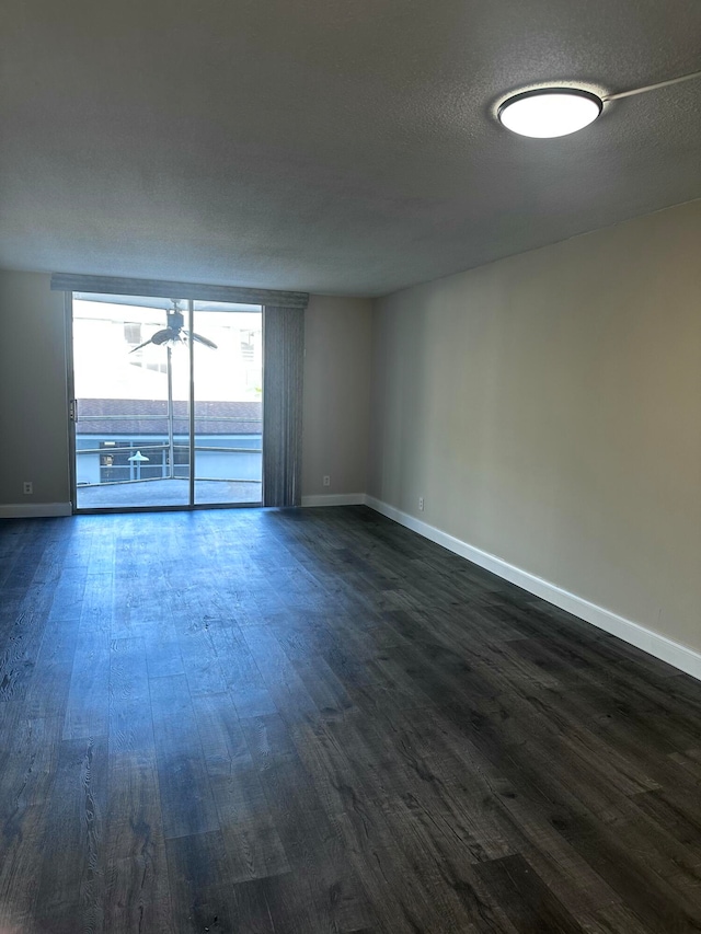 empty room with dark wood-type flooring, a textured ceiling, and ceiling fan