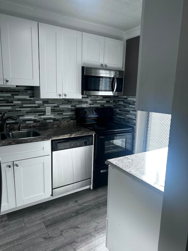 kitchen with dark wood-type flooring, ornamental molding, sink, white cabinetry, and appliances with stainless steel finishes