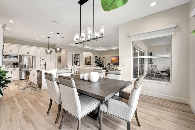 dining area with sink, light hardwood / wood-style flooring, and a chandelier