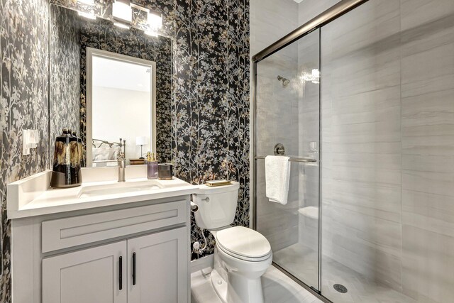 bathroom featuring vanity, a shower with shower door, and toilet