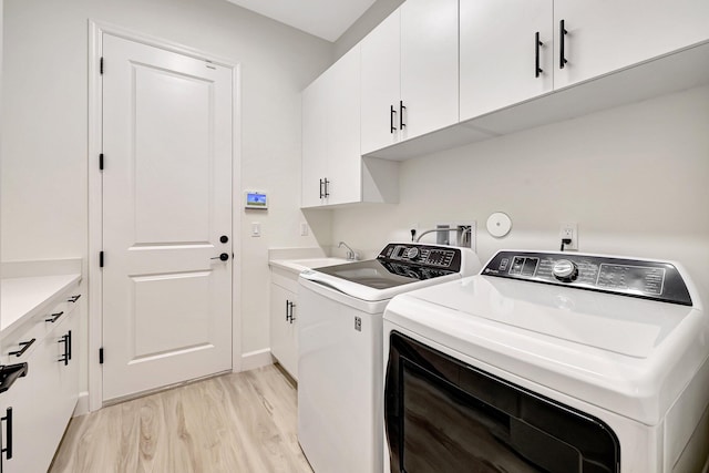 laundry area featuring cabinets, light hardwood / wood-style flooring, independent washer and dryer, and sink