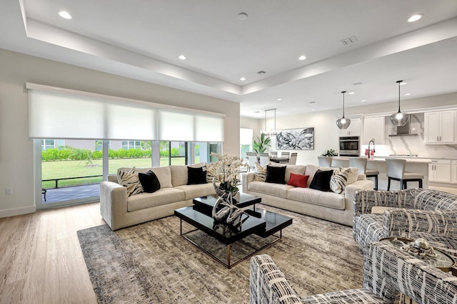 living room with a tray ceiling and light wood-type flooring