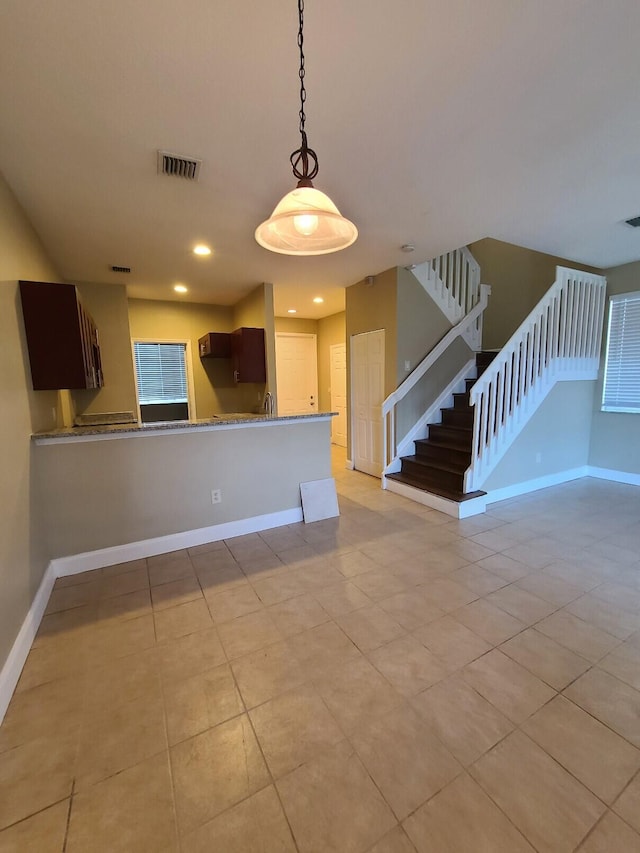 kitchen featuring dark brown cabinets, light tile patterned floors, and kitchen peninsula