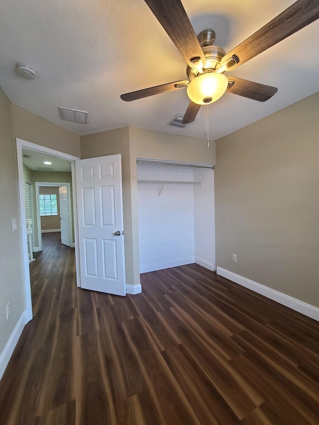 unfurnished bedroom featuring a closet, ceiling fan, and dark hardwood / wood-style flooring