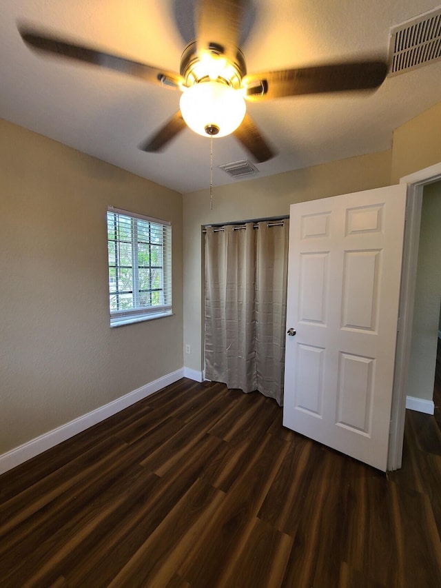 unfurnished bedroom with dark wood-type flooring and ceiling fan