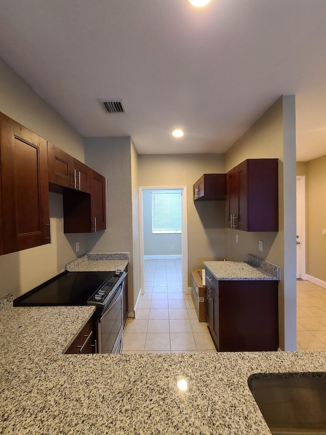 kitchen with stainless steel electric stove, light stone counters, and light tile patterned floors