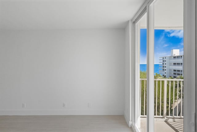 spare room with a water view, light hardwood / wood-style floors, and a wall of windows