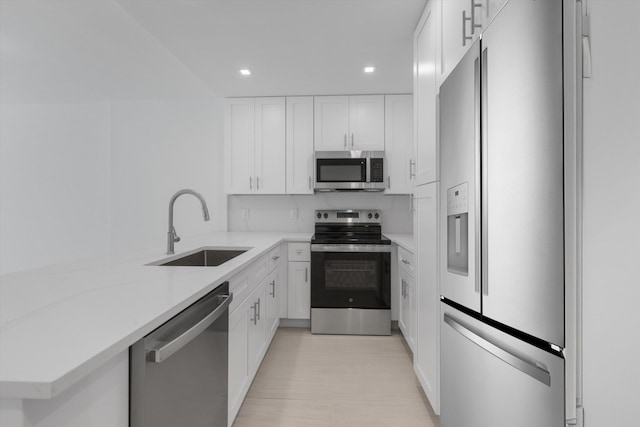 kitchen featuring white cabinetry, stainless steel appliances, sink, and light stone counters