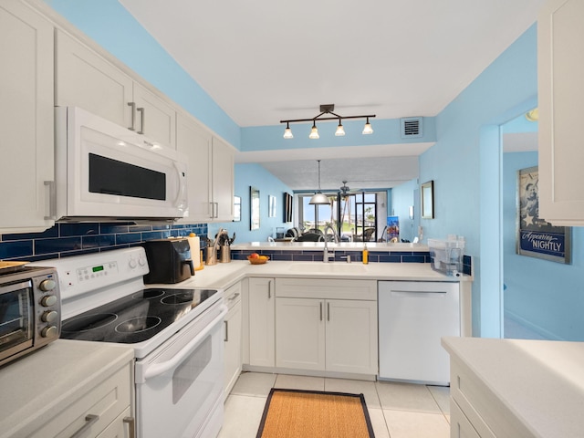 kitchen with white appliances, tasteful backsplash, sink, kitchen peninsula, and white cabinets