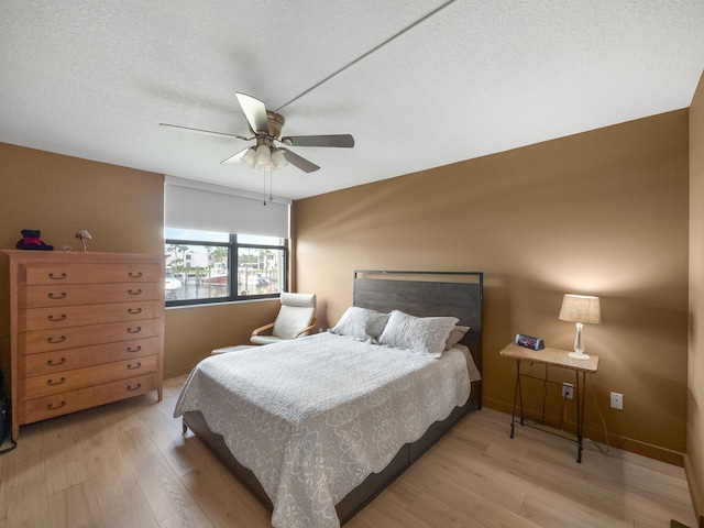 bedroom featuring a textured ceiling, light hardwood / wood-style floors, and ceiling fan