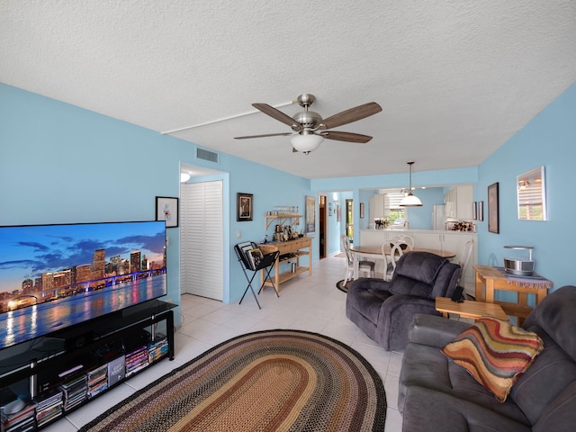 living room with a textured ceiling, light tile patterned floors, and ceiling fan