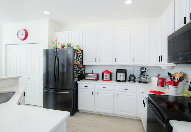 kitchen featuring white cabinets, light hardwood / wood-style floors, black appliances, and decorative backsplash