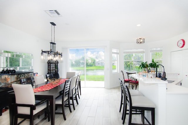 dining room featuring sink, a notable chandelier, and light hardwood / wood-style flooring