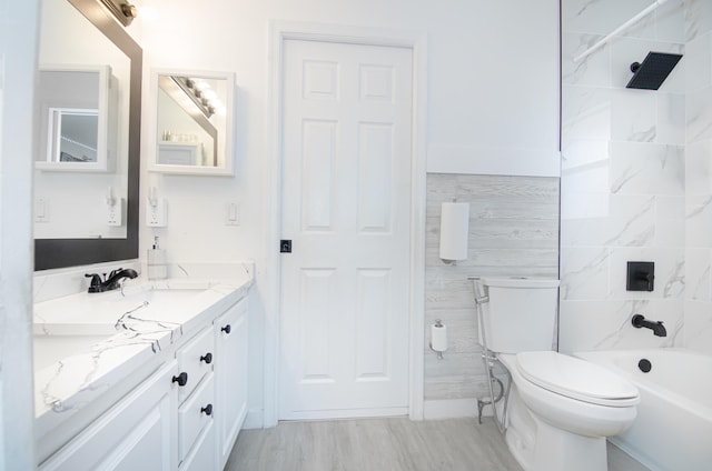 full bathroom with tile walls, vanity, tiled shower / bath combo, hardwood / wood-style flooring, and toilet