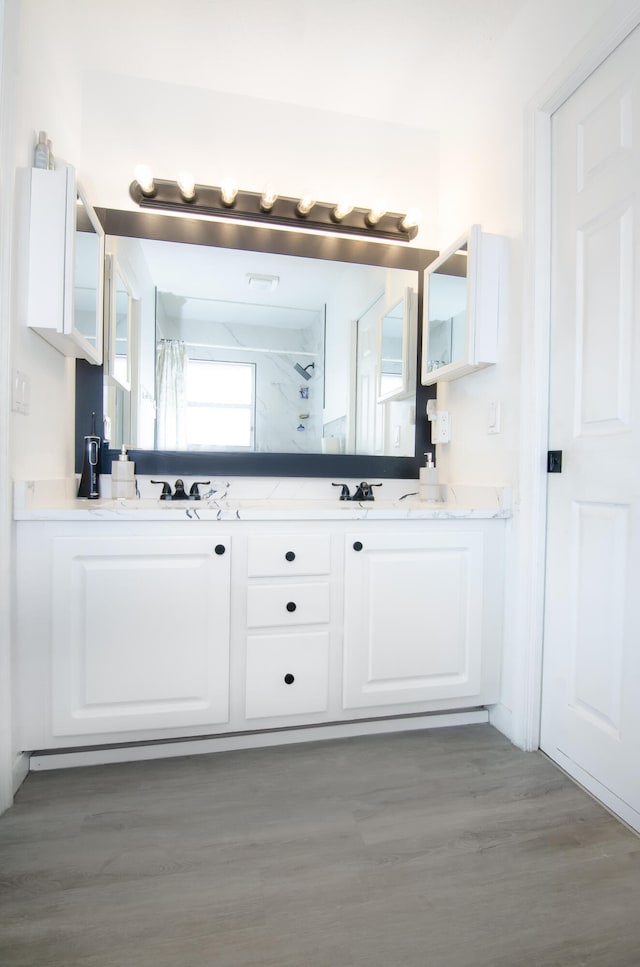 bathroom with wood-type flooring, a shower with shower curtain, and vanity