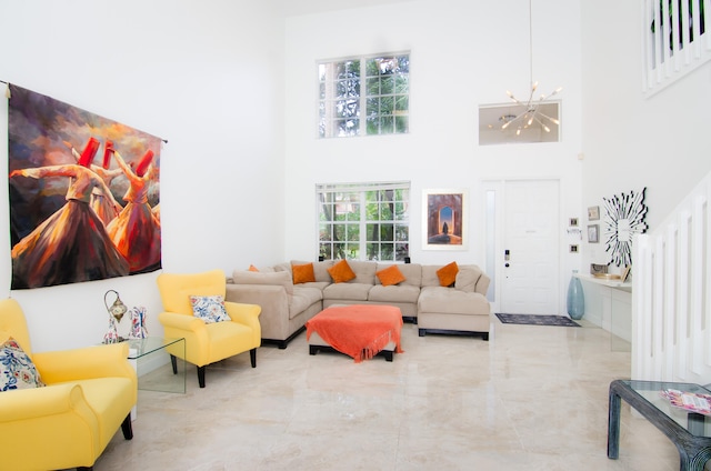 living room with a towering ceiling, a chandelier, and a wealth of natural light