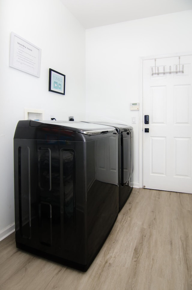 laundry room featuring light wood-type flooring and separate washer and dryer