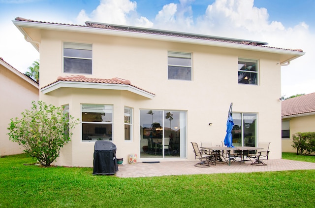 rear view of property featuring a lawn and a patio