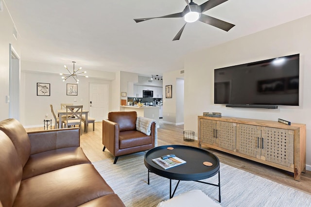 living room featuring light hardwood / wood-style flooring and ceiling fan with notable chandelier